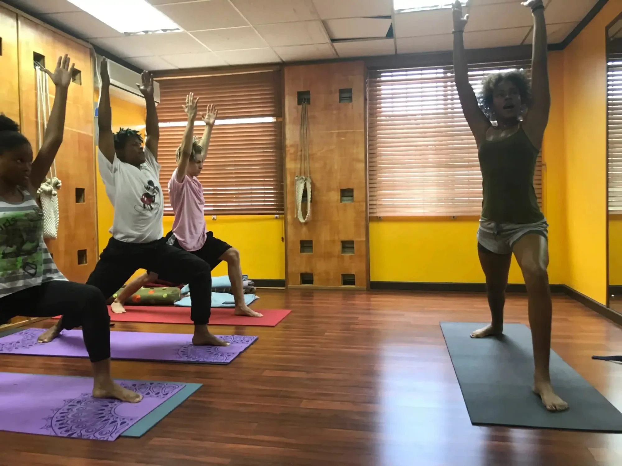 Adults in a studio standing in a lunge with arms raised